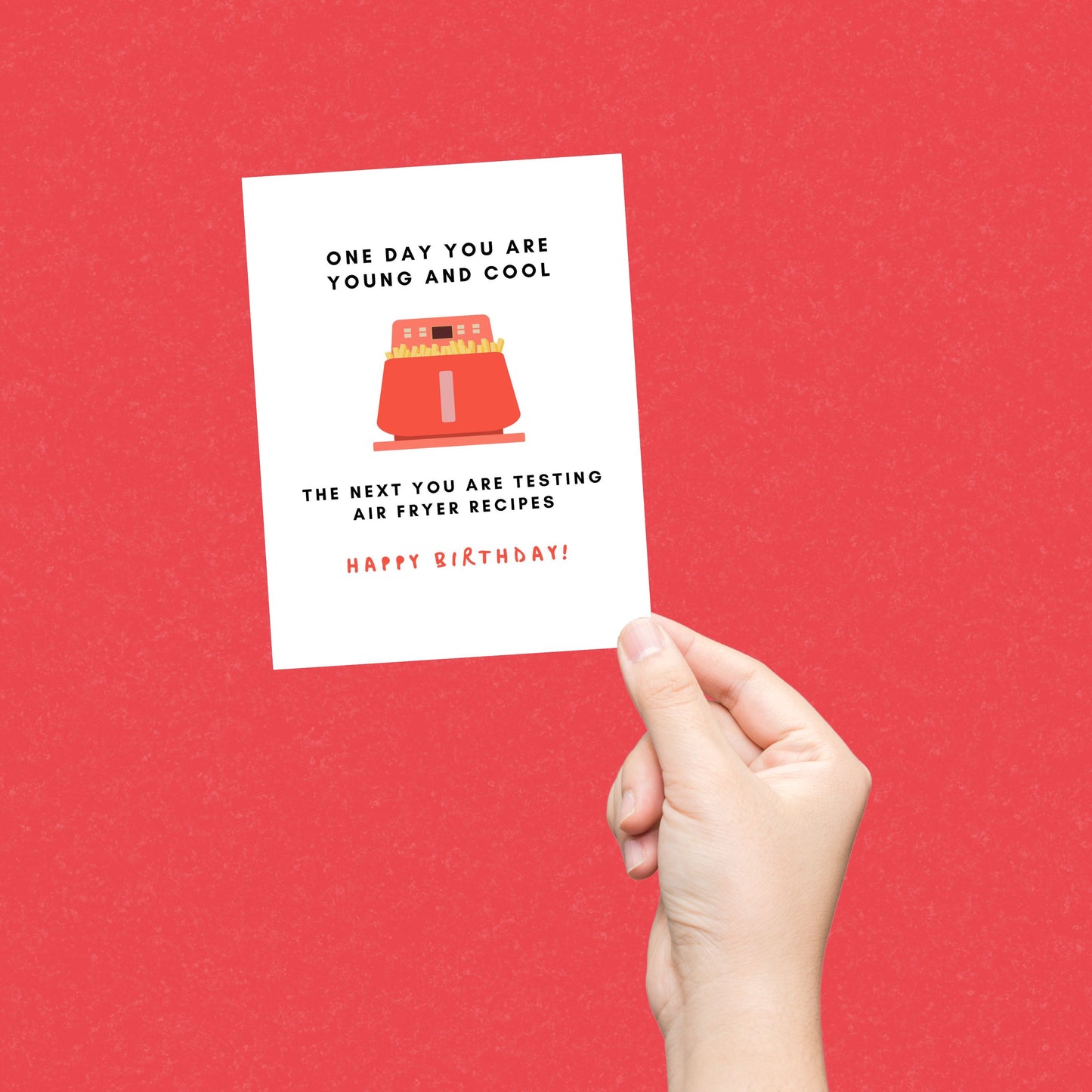 Birthday greeting card with the phrase One Day You Are Young And Cool, The Next You Are Testing Air Fryer Recipes featuring a drawing of a red air fryer and Happy Birthday written at the bottom. Perfect for celebrating with humor and relatable twist.