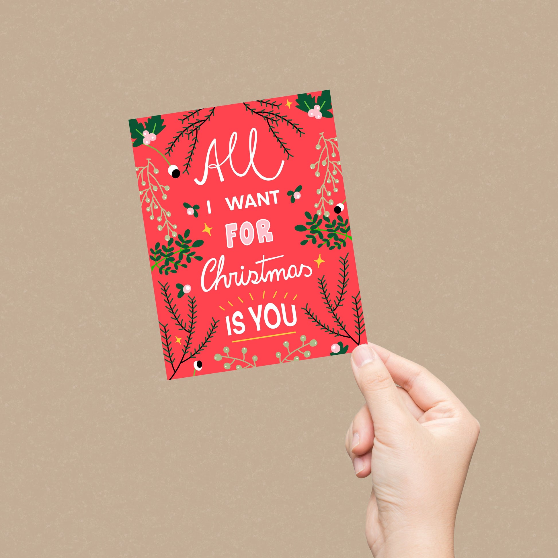 Christmas greeting card with the phrase All I Want For Christmas Is You on a red background with greenery on the borders. Perfect for expressing love and holiday cheer with joy and charm.