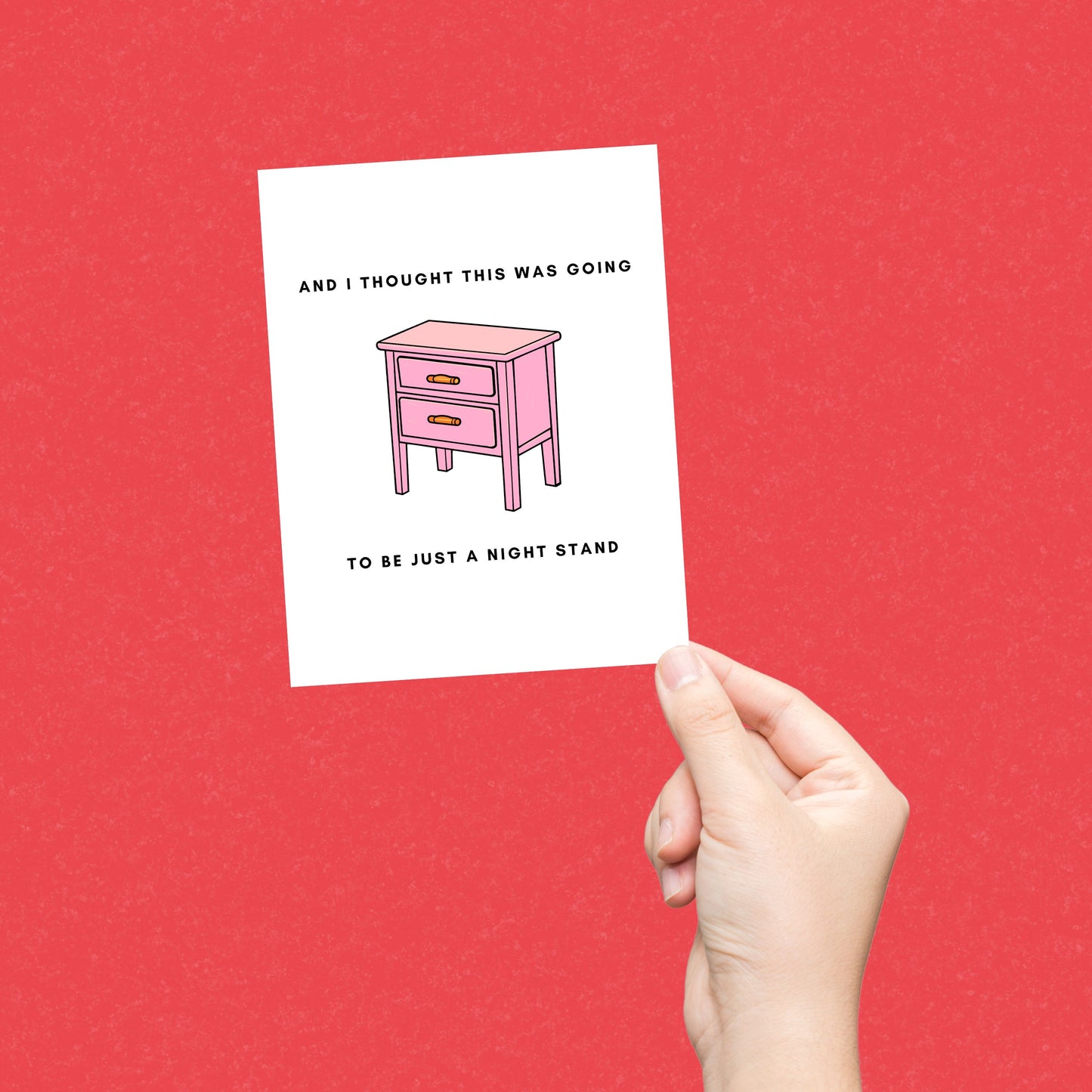 Greeting card with the phrase And I Thought This Was Going to Be a Night Stand featuring an illustration of a pink nightstand with two drawers. Perfect for celebrating relationships with a humorous and cheeky touch.