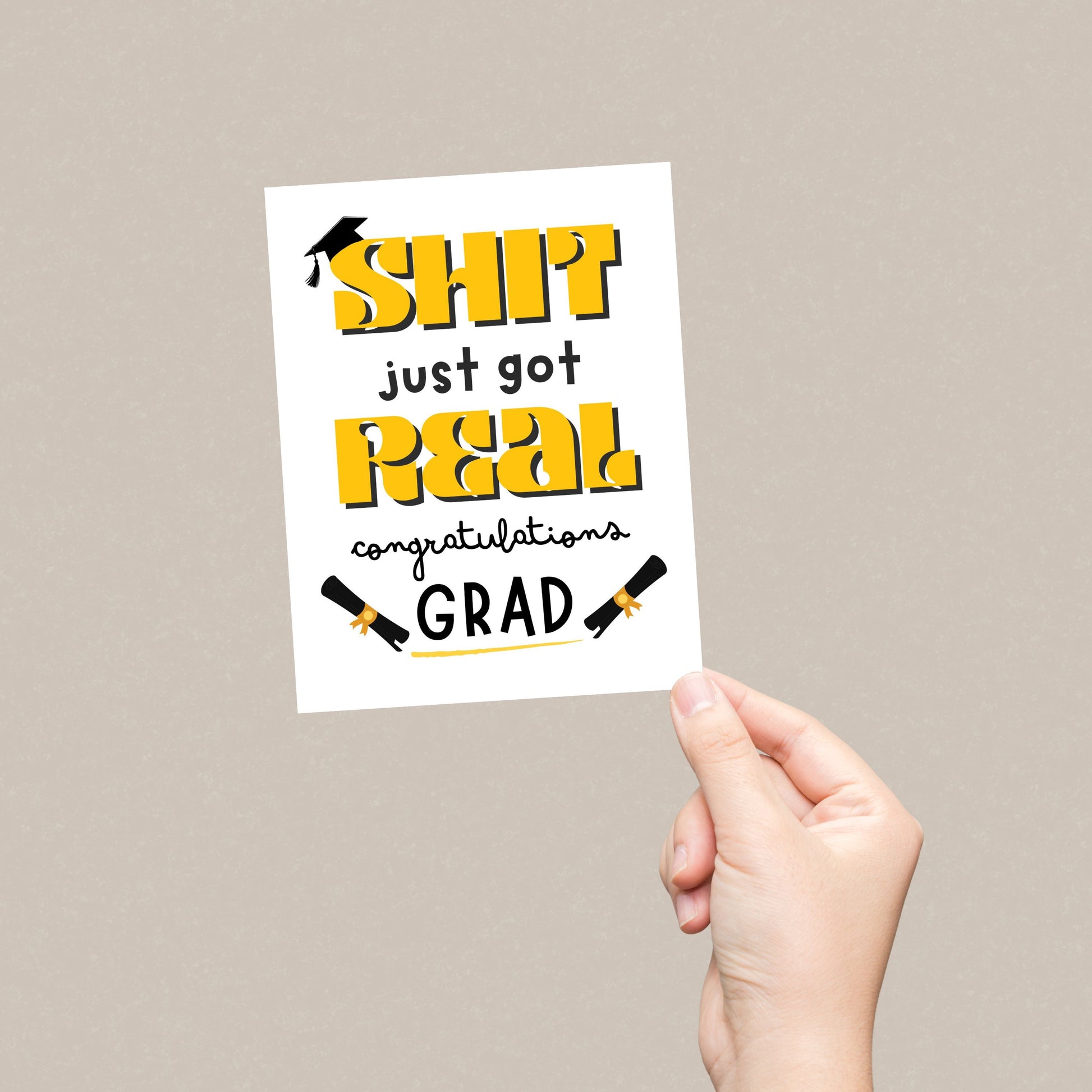 Funny graduation card with a black graduation cap, two rolled diplomas, and the phrase "Shit Just Got Real, Congratulations Grad" in bold letters. Perfect for high school or college graduates with a sense of humor.