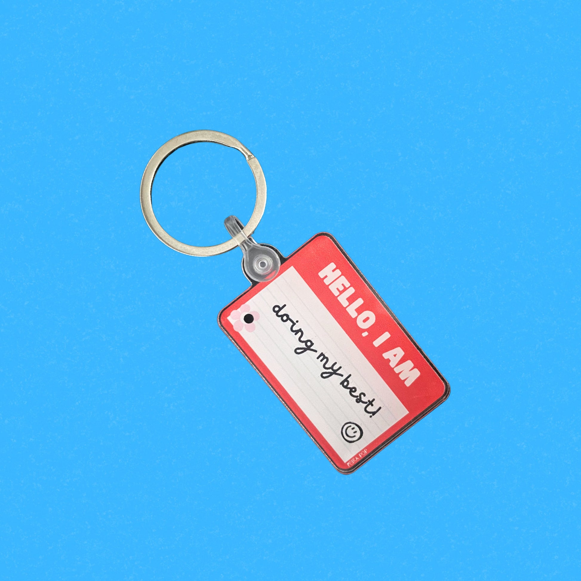 Red name tag keychain with the phrase Hello, I Am Doing My Best, humorous motivational accessory, perfect for daily encouragement and resilience, ideal gift for friends and family.