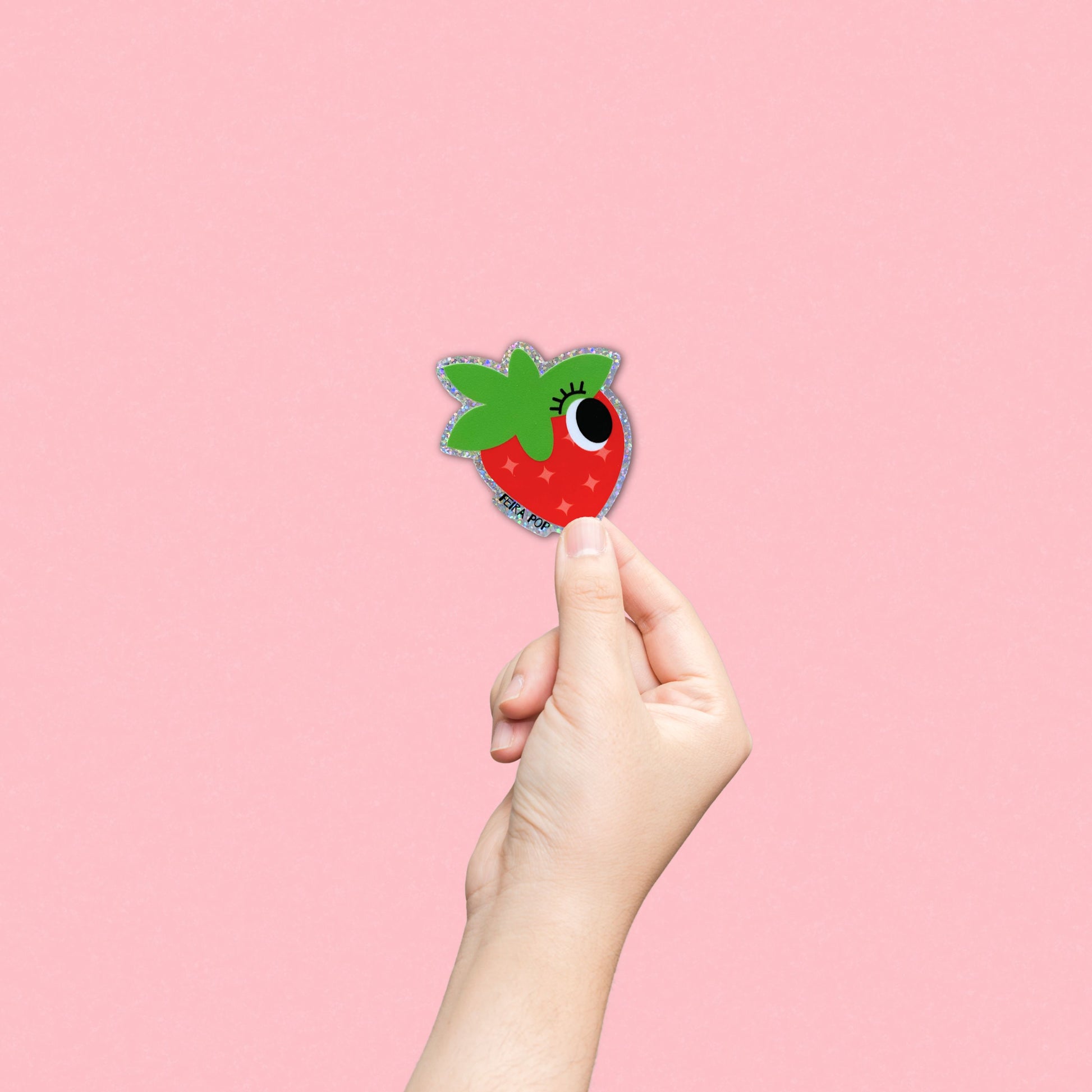 Glitter sticker with a cute strawberry drawing featuring one big eye, perfect for adding a playful and sparkly touch to your belongings.
