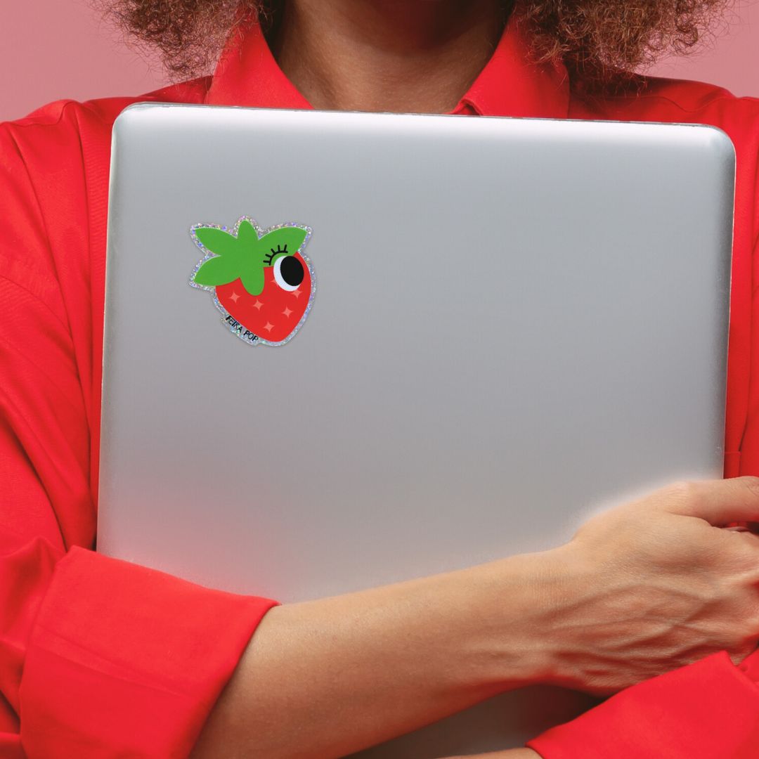Glitter sticker with a cute strawberry drawing featuring one big eye, perfect for adding a playful and sparkly touch to your belongings.