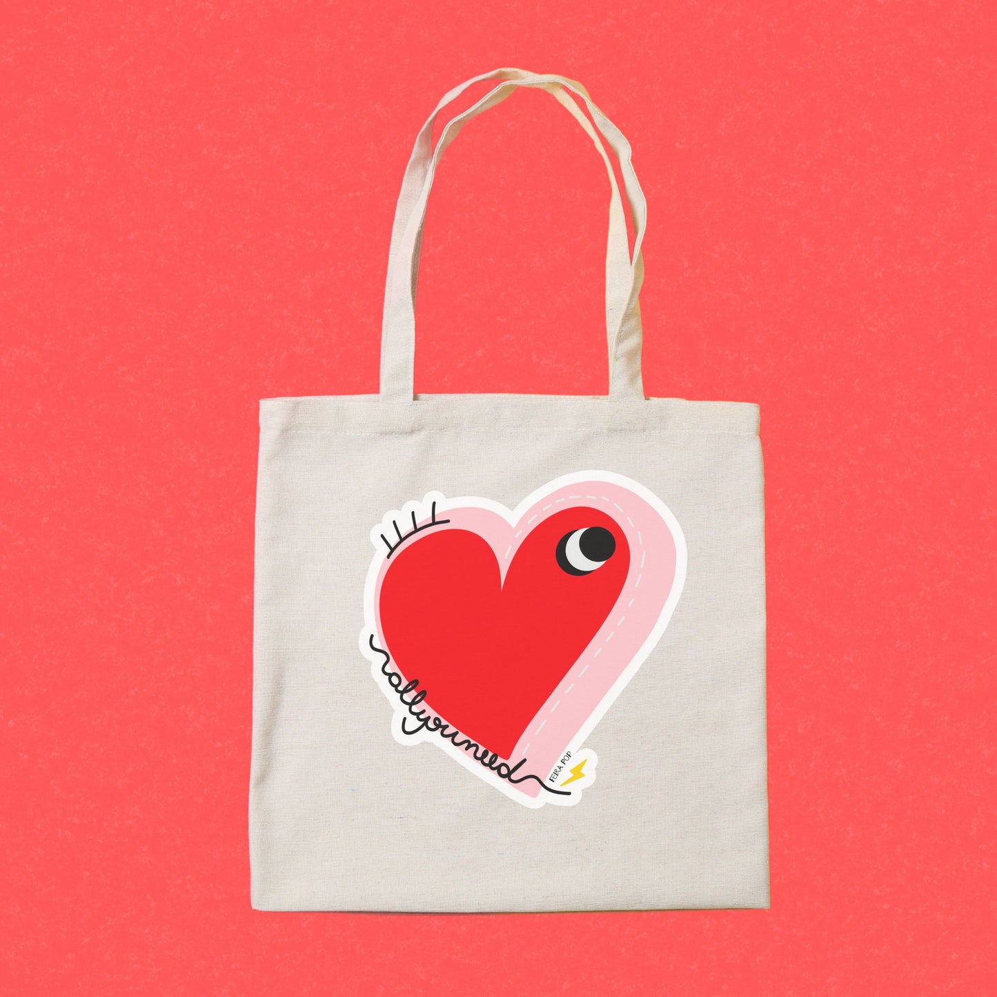 All You Need Tote Bag with original drawing of a big red heart with one eye and the words All You Need in playful font, perfect for carrying daily essentials and adding a touch of fun to any outfit.
