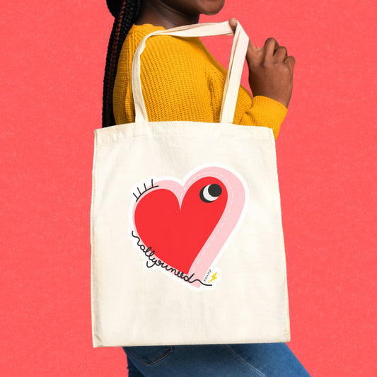All You Need Tote Bag with original drawing of a big red heart with one eye and the words All You Need in playful font, perfect for carrying daily essentials and adding a touch of fun to any outfit.