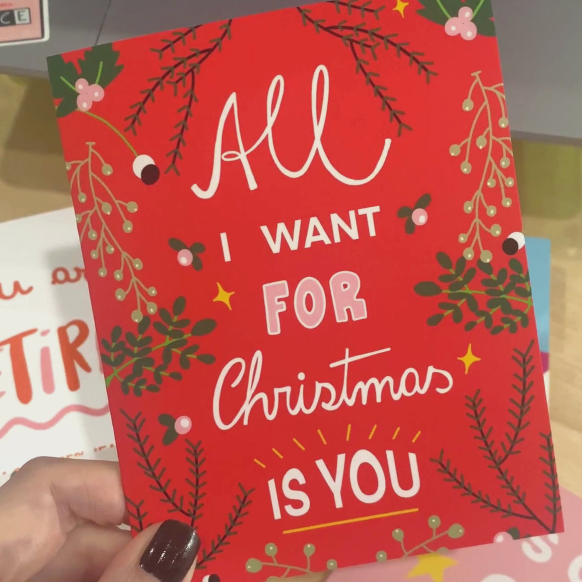 Christmas greeting card with the phrase All I Want For Christmas Is You on a red background with greenery on the borders. Perfect for expressing love and holiday cheer with joy and charm.