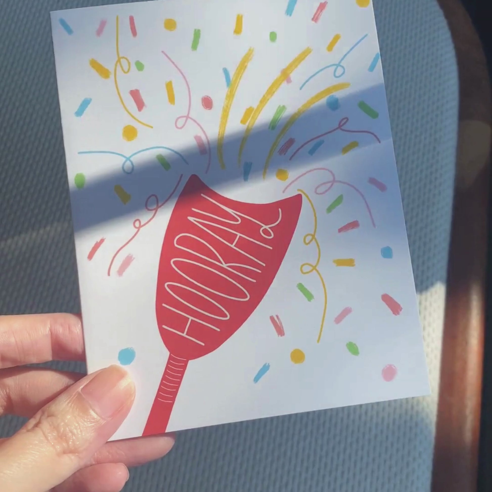 Greeting card with the word Hooray written in a party popper, featuring an original drawing of a party popper and colorful confetti flying out. Perfect for celebrating any joyous occasion with a festive and humorous touch.