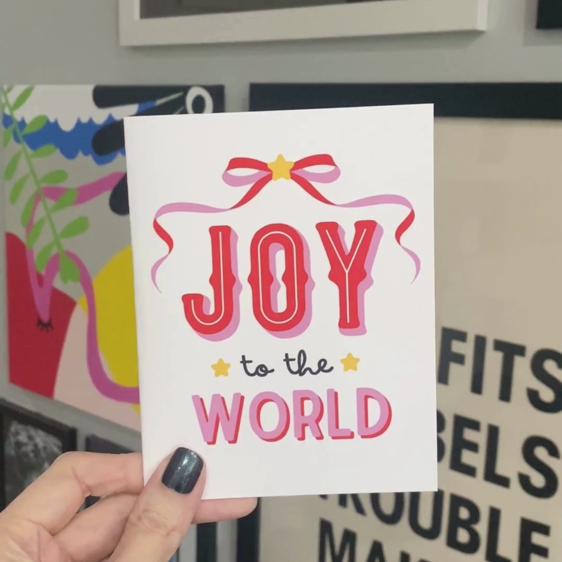 Christmas greeting card with a pink and red bow design, featuring the festive phrase Joy To The World in bold lettering, perfect for spreading holiday cheer with a fun and playful touch.