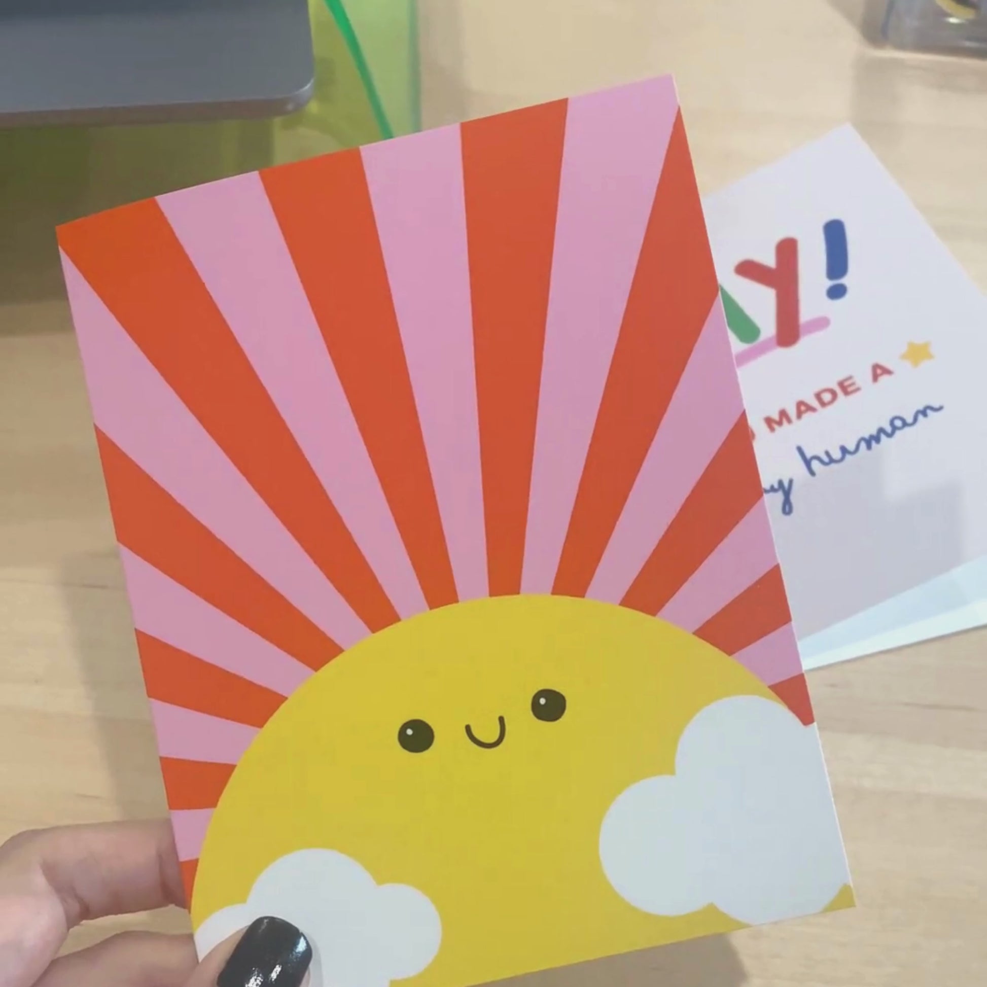 Sunshine Greeting Card with a drawing of a big yellow sun with a smiling face, pink and red rays, and two clouds. Blank inside, perfect for spreading cheerful vibes and warm wishes.