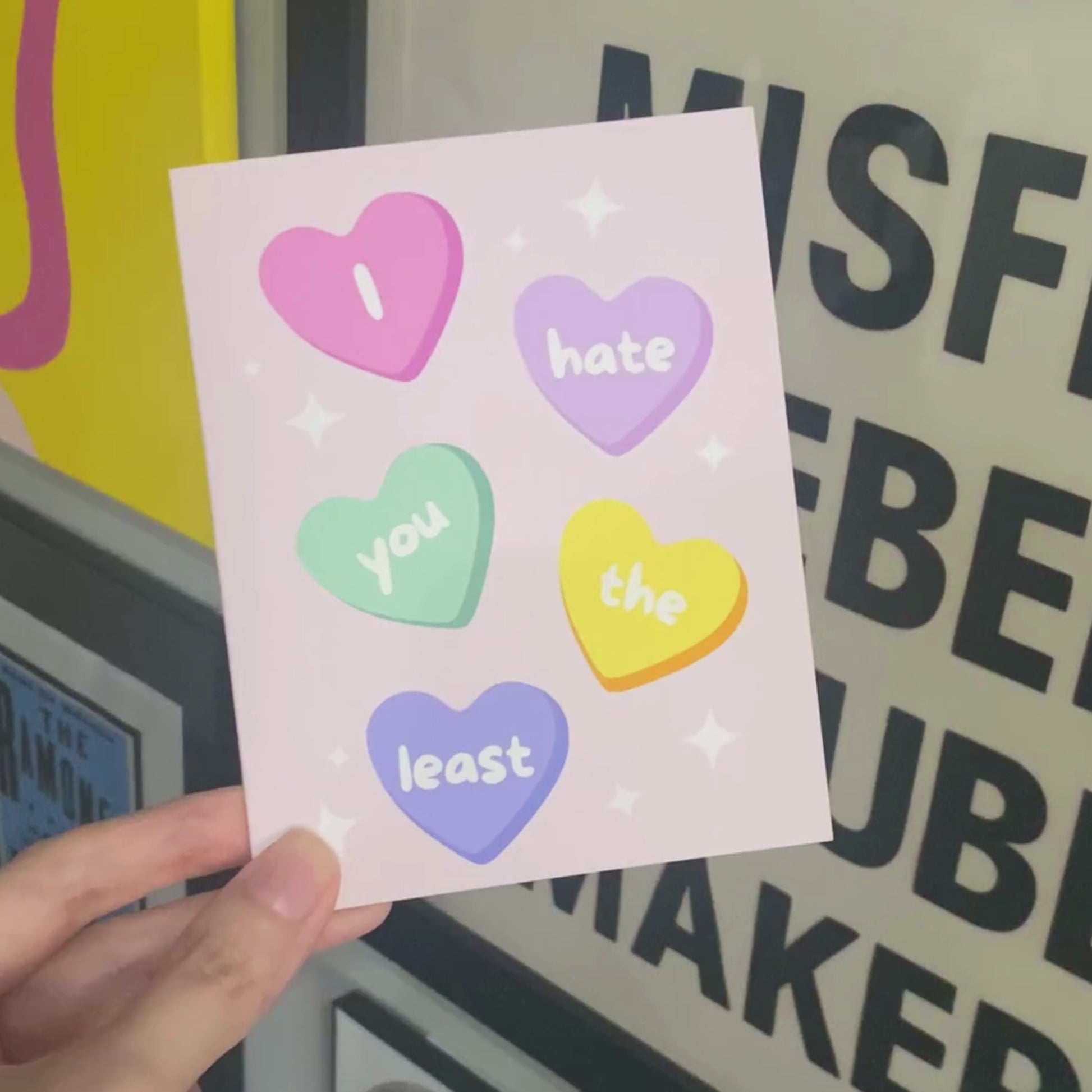 Funny greeting card with conversation heart candies, each displaying a word from the phrase 'I Hate You The Least.' Playful and humorous design perfect for Valentine's Day, friendships, or lighthearted occasions.