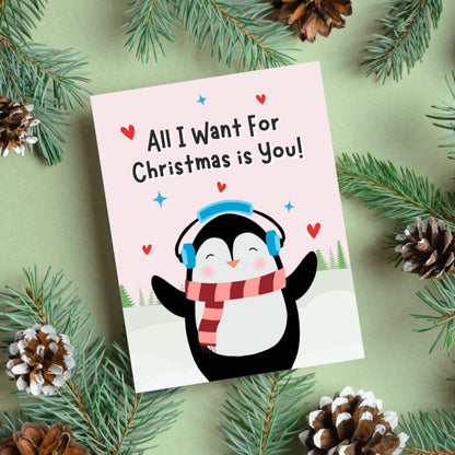 Cute Christmas card featuring an adorable penguin standing in a snowy winter scene with the phrase “All I Want For Christmas Is You.” Festive holiday card perfect for couples, romantic Christmas greetings, and seasonal gifting.