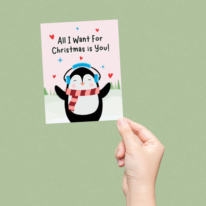 Cute Christmas card featuring an adorable penguin standing in a snowy winter scene with the phrase “All I Want For Christmas Is You.” Festive holiday card perfect for couples, romantic Christmas greetings, and seasonal gifting.