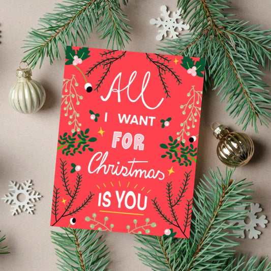 Christmas greeting card with the phrase All I Want For Christmas Is You on a red background with greenery on the borders. Perfect for expressing love and holiday cheer with joy and charm.