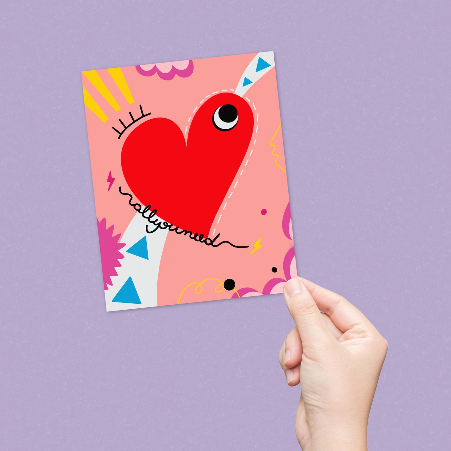 Greeting card with the phrase All you Need featuring a drawing of a big red heart with one eye and a colorful background. Perfect for celebrating any occasion with a playful and heartfelt touch.