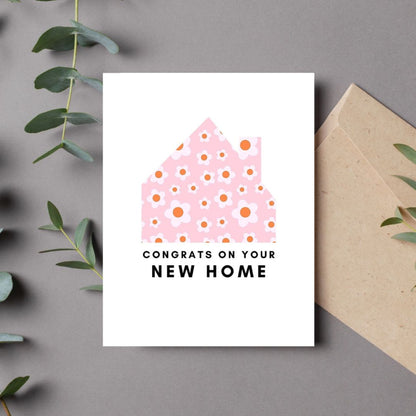 New home greeting card with a pink and white floral house design and the phrase "Congrats on Your New Home." Perfect for housewarming gifts, first-time homeowners, and moving celebrations. Ideal for real estate agents and thoughtful well-wishers.