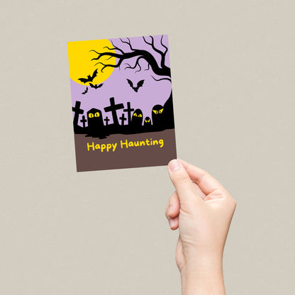 Halloween greeting card with a spooky cemetery illustration, tombstones, and a full moon, featuring the phrase Happy Haunting in bold letters. Perfect for sending Halloween wishes to friends and family.