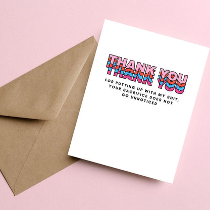 Greeting card with colorful block letters spelling Thank You and smaller text reading for putting up with my shit your sacrifice does not go unnoticed. Perfect for expressing gratitude with humor and a personal touch.