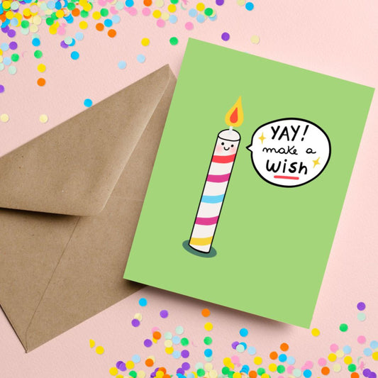 Birthday greeting card with the phrase Yay Make A Wish featuring an original drawing of a colorful smiley face candle on a green background. Perfect for celebrating birthdays with a cute and whimsical touch.