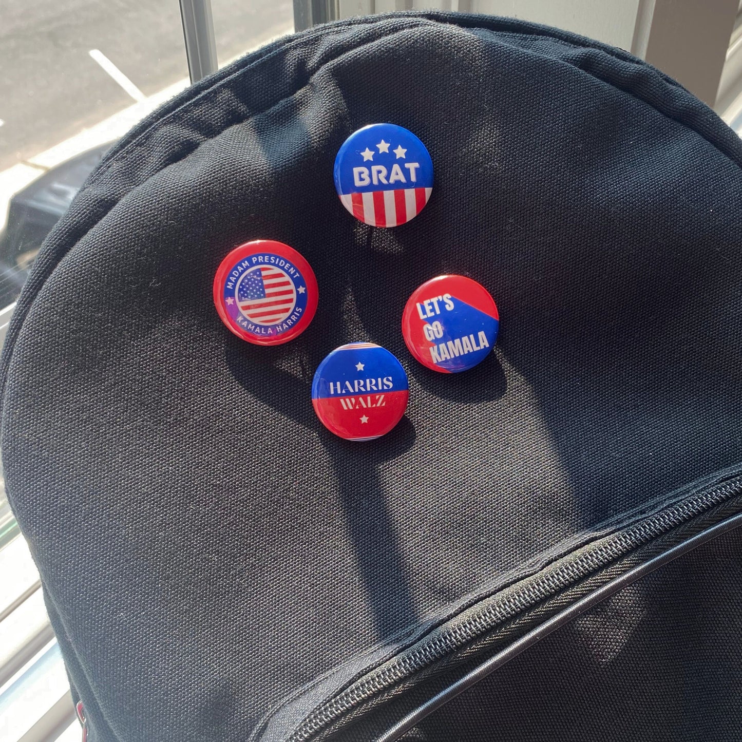 4-pin back button pack supporting Kamala Harris presidential run, featuring messages 'Madam President Kamala Harris,' 'Brat,' 'Let's Go Kamala,' and 'Harris/Walz.' Perfect for showing political support and style.