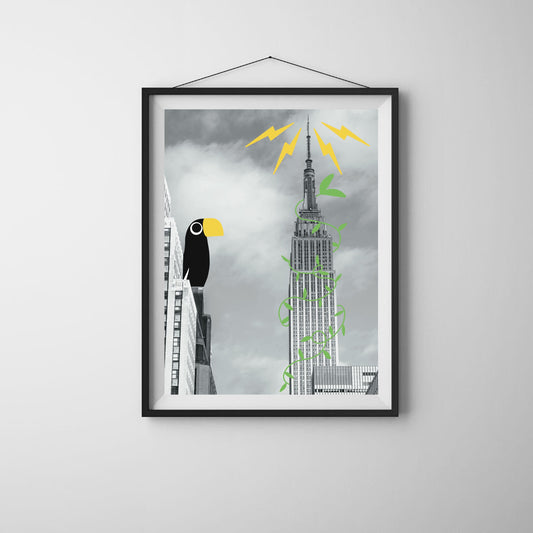 Black and white art print of the Empire State Building with illustrated tropical vines and a colorful toucan perched on a nearby building. Fun surreal wall art titled “Tropical Empire,” perfect for city lovers and modern home decor.
