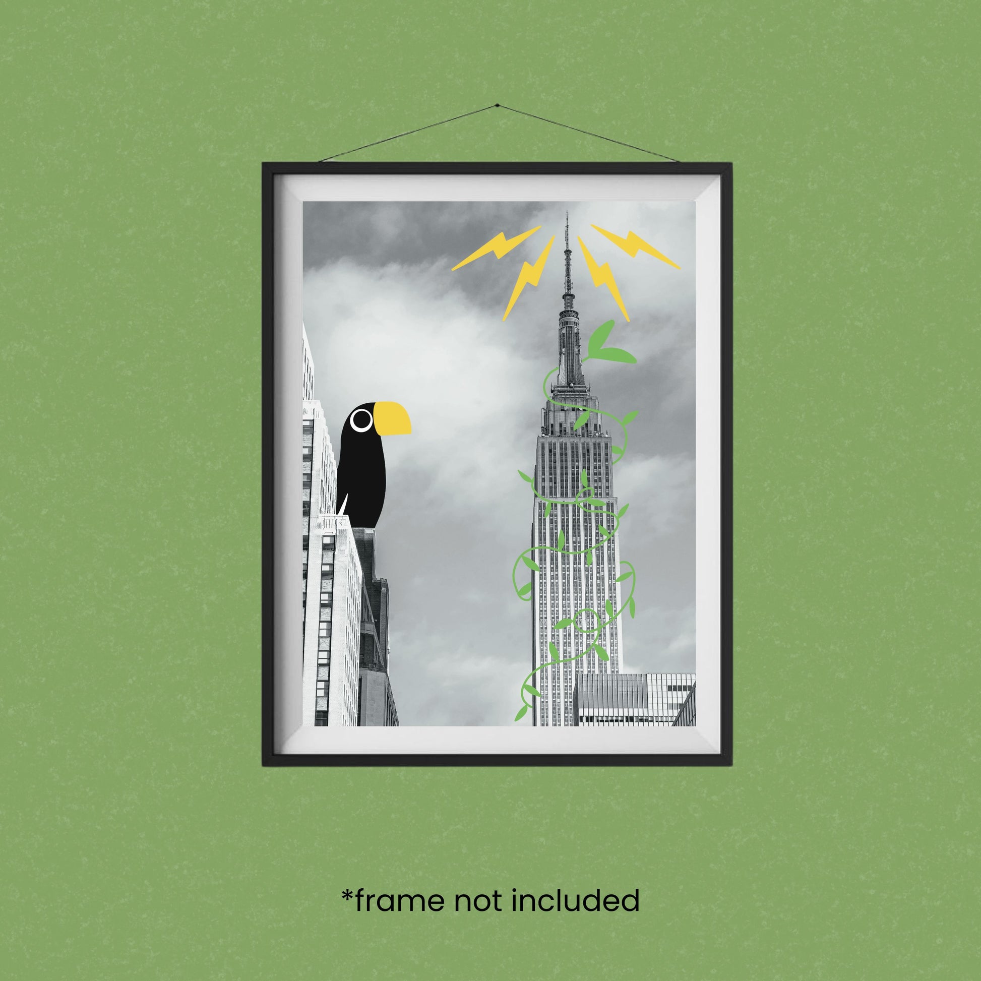 Black and white art print of the Empire State Building with illustrated tropical vines and a colorful toucan perched on a nearby building. Fun surreal wall art titled “Tropical Empire,” perfect for city lovers and modern home decor.