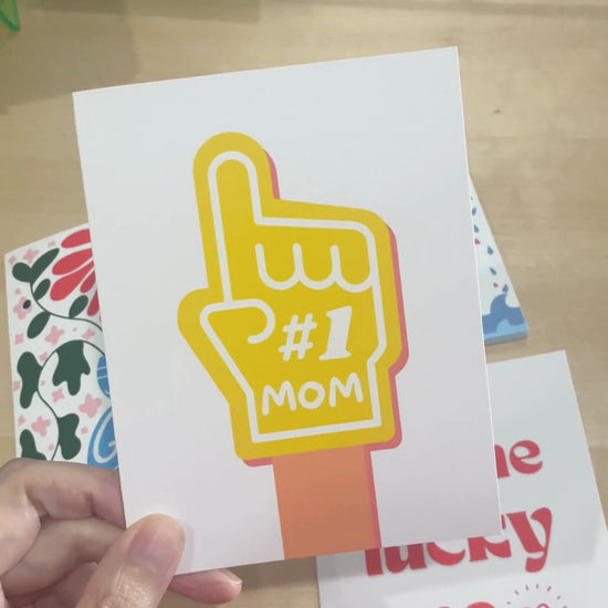 Number One Mom greeting card with a big yellow foam finger featuring #1 MOM, perfect for celebrating the best mom ever, Mother’s Day card, fun and playful mom appreciation card.