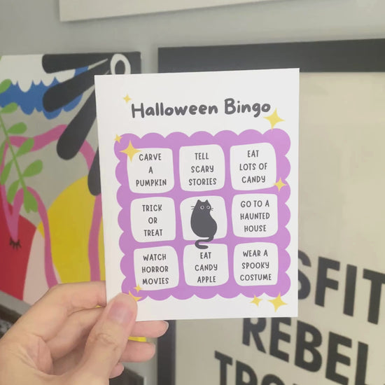 Halloween greeting card featuring a cute bingo card with spooky activities like spotting a black cat, visiting a haunted house, watching horror movies, and eating candy, perfect for Halloween enthusiasts who love festive fun.