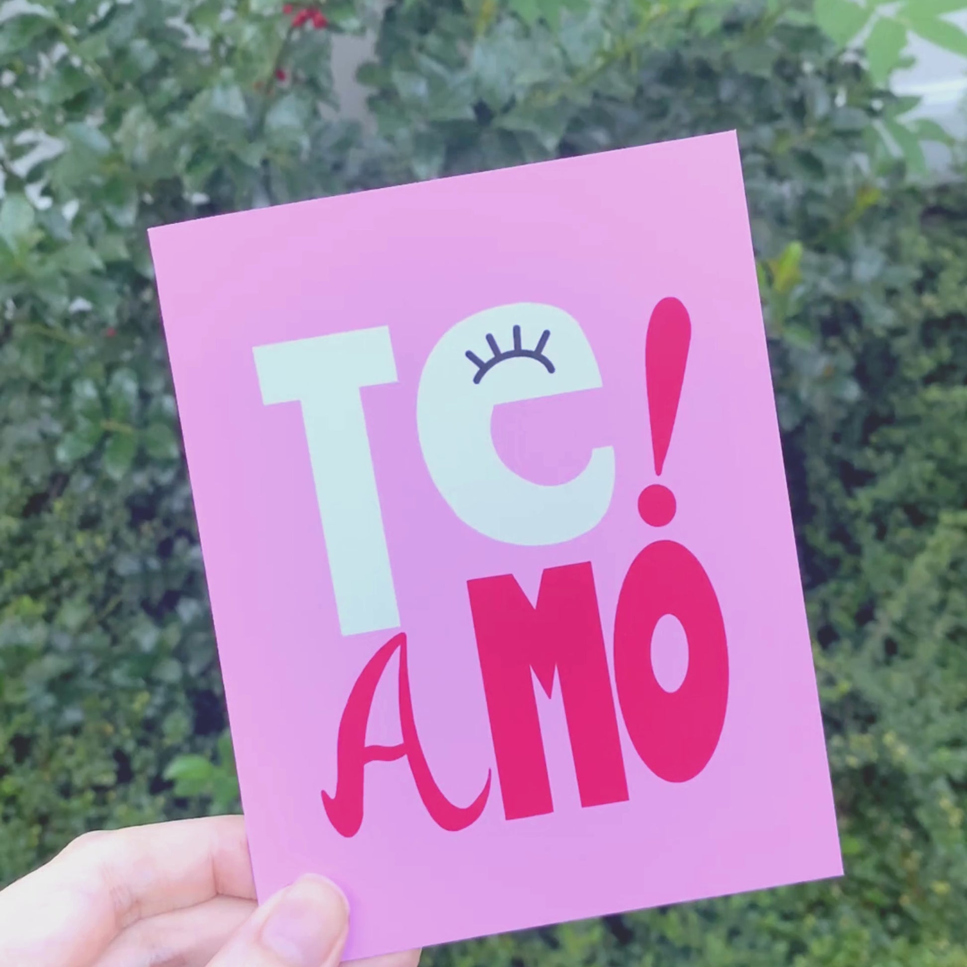 Te Amo greeting card with pink background, perfect for expressing love and affection, playful and whimsical design, ideal for anniversaries, special occasions, or just because, heartfelt and fun way to say "I love you" in Spanish and Portuguese.